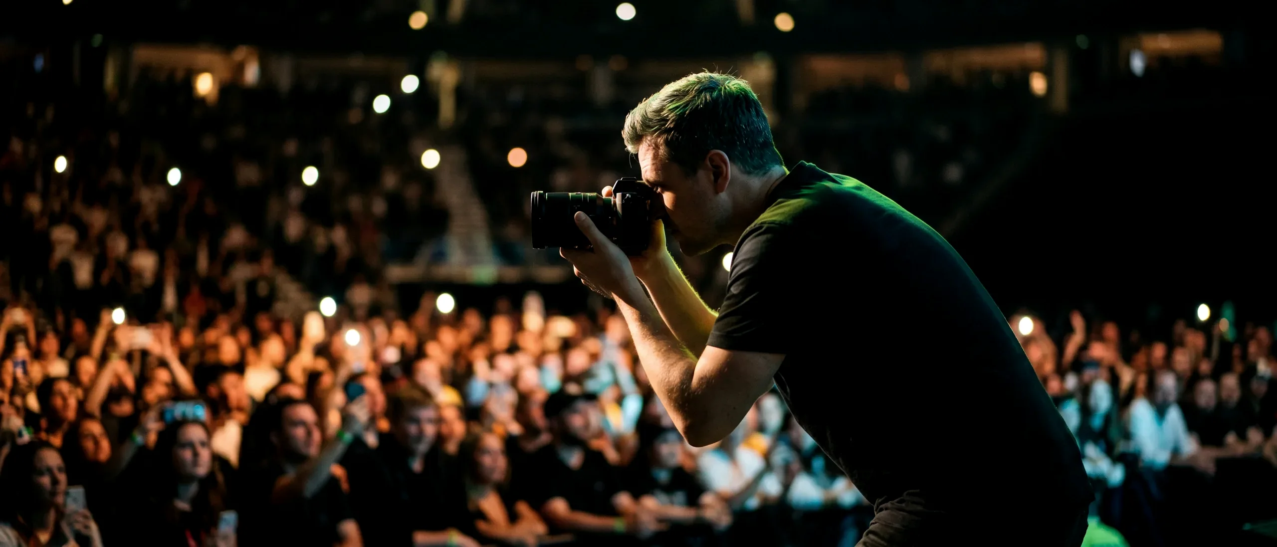 A confident photographer working a night venue, crowd lit behind